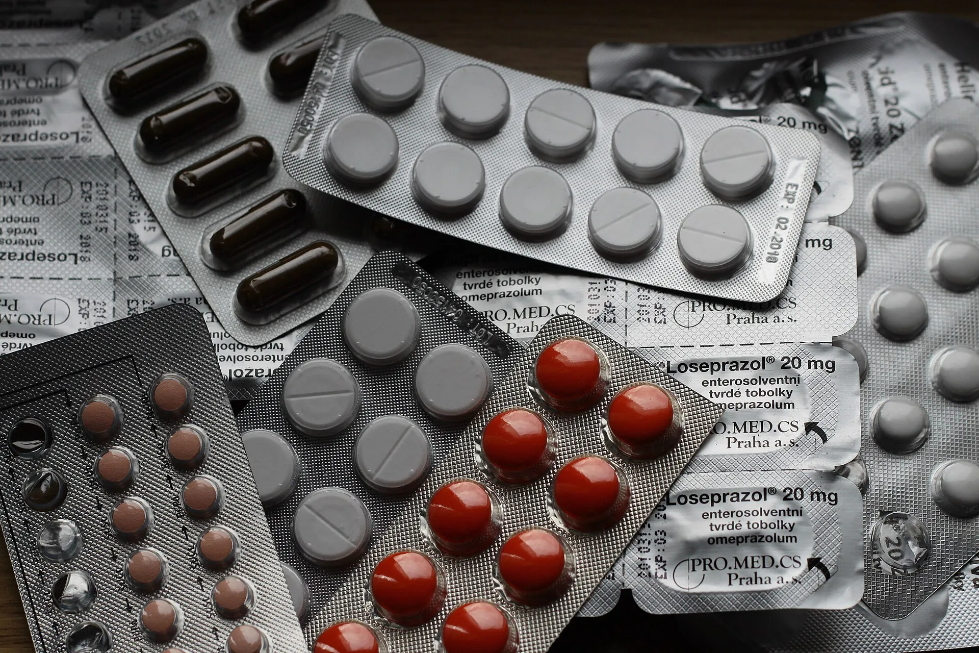 Blister strips of tablets and capsules heaped together, some printed with brand names